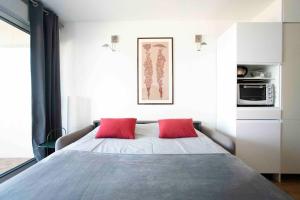 een slaapkamer met een bed met twee rode kussens erop bij *STUDIO*VUE BASSIN*ACCES DIRECT À LA PLAGE*WIFI* in Arcachon