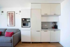 een witte keuken met een bank en een magnetron bij *STUDIO*VUE BASSIN*ACCES DIRECT À LA PLAGE*WIFI* in Arcachon