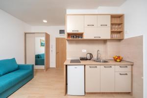 a kitchen with white cabinets and a blue couch at Apartments Bonazza in Petrovac na Moru