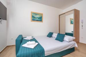 a bedroom with a large white bed with blue accents at Apartments Bonazza in Petrovac na Moru