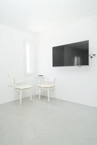 a white room with two tables and a flat screen tv at Suite Agia Irene Kythnos in Kakóvolon