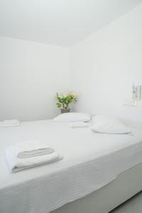 a white bed with white sheets and a vase of flowers at Suite Agia Irene Kythnos in Kakóvolon