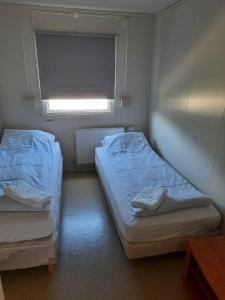 2 camas en una habitación pequeña con ventana en Vinland Apartment 2, en Egilsstadir
