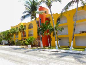 a yellow building with palm trees in front of it at Hotel Ma Elena in Isla Mujeres