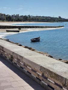 un pequeño barco en el agua junto a una playa en Apartamento Parque Bahía, en Puerto Real
