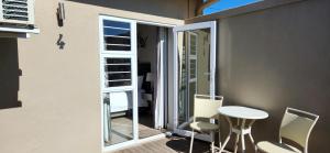 uma pequena varanda com cadeiras, uma mesa e uma porta em Green Kalahari Guesthouse em Upington