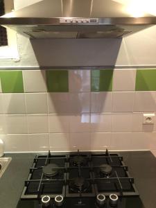 a stove top in a kitchen with green and white tiles at LIMOUX RIVERSIDE GARDENs in Limoux