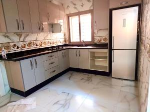 a large kitchen with white cabinets and a refrigerator at Apartment 3 kamers Nador Jadid Hay Al Matar appart 006 in Nador