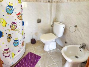 a bathroom with a toilet and a shower curtain with owls at Villa Blanca in Utjeha