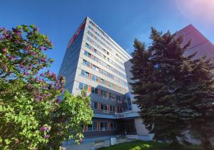 a tall white building with a tree in front of it at Abitohotel in Prague