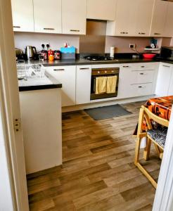 a kitchen with white cabinets and a wooden floor at House with Breath of Fresh Air in Bloxwich