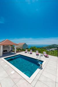 uma piscina com cadeiras e o oceano ao fundo em Villa Vista em Mlini