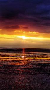 una puesta de sol sobre el océano con la puesta de sol en Thistledew, en Hunstanton
