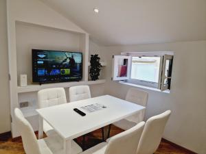 a dining room with a white table and a tv at HomeHoliday LUXE - MY PLACE SANREMO in Sanremo