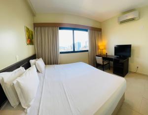 a bedroom with a large white bed and a desk at Hotel Saint Paul in Manaus