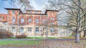 ein großes Backsteingebäude mit einem Baum davor in der Unterkunft Residenz unter den Linden Falke in Mühlhausen