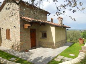 una pequeña casa de piedra con puerta roja en Selva degli Ulivi, en Foiano della Chiana