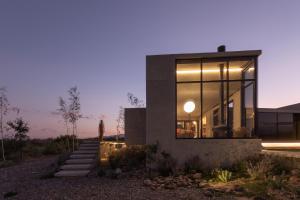 a modern house with glass windows and stairs at Casa de Uco Vineyards and Wine Resort in Los Árboles