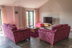 a living room with two chairs and a tv at Gaer Fawr Barns in Guilsfield