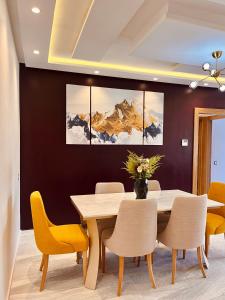 Appartement moderne au décor raffiné في القنيطرة: غرفة طعام مع طاولة خشبية وكراسي صفراء
