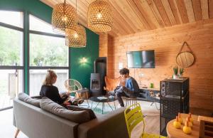 two people sitting on a couch in a living room at Huttopia Etang Fouché in Arnay-le-Duc