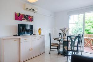 ein Wohnzimmer mit einem TV und einem Esstisch in der Unterkunft Appartement Gran Reserva 9 - WeHostYou in Empuriabrava