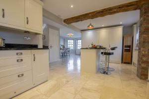 a kitchen with white cabinets and a table in a room at Saxon House 7 in Harome