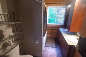 La salle de bains est pourvue de toilettes, d'un lavabo et d'une fenêtre. dans l'établissement Le relaxant chalet du petit ruisseau, à Mandeville