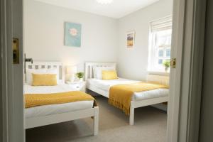 een slaapkamer met 2 bedden met gele lakens en een raam bij Saxon House 7 in Harome