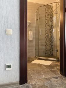 uma casa de banho com um chuveiro e uma porta de vidro em Seaside Apartment em Batumi