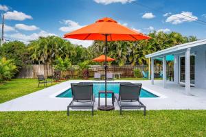 a patio with two chairs and an umbrella next to a pool at Spacious 5 Bedrooms with Large Pool, 12 minutes to the Ocean in Fort Lauderdale