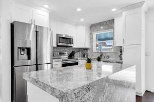 a white kitchen with a large marble counter top at Spacious 5 Bedrooms with Large Pool, 12 minutes to the Ocean in Fort Lauderdale