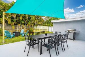 a black table and chairs with a blue umbrella at Spacious 5 Bedrooms with Large Pool, 12 minutes to the Ocean in Fort Lauderdale