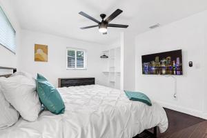 a bedroom with a white bed with a ceiling fan at Spacious 5 Bedrooms with Large Pool, 12 minutes to the Ocean in Fort Lauderdale