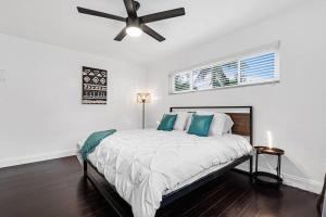 a white bedroom with a bed with a ceiling fan at Spacious 5 Bedrooms with Large Pool, 12 minutes to the Ocean in Fort Lauderdale
