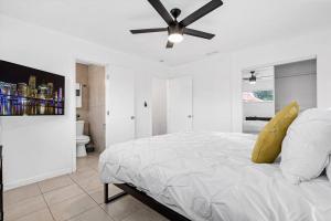 a white bedroom with a bed with a ceiling fan at Spacious 5 Bedrooms with Large Pool, 12 minutes to the Ocean in Fort Lauderdale