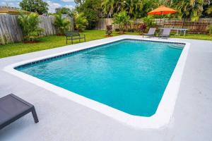 a swimming pool with a table and chairs and an umbrella at Spacious 5 Bedrooms with Large Pool, 12 minutes to the Ocean in Fort Lauderdale
