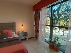 1 dormitorio con cama y ventana grande en MENDOZA Suites 8 en Mendoza