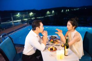 mężczyzna i kobieta siedzący przy stole jedzący jedzenie w obiekcie Minh Chau Pearl Hotel & Spa - Quan Lan Island w mieście Quang Ninh