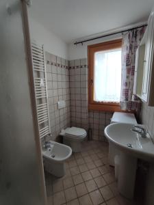 a bathroom with two sinks and a toilet and a window at Appartamenti Flora Alpina in Temù