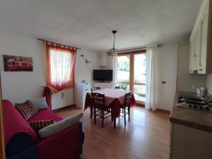 a living room with a table and a couch and a kitchen at Appartamenti Flora Alpina in Temù