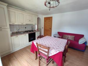 a kitchen with a table and a couch in a room at Appartamenti Flora Alpina in Temù
