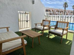 3 Stühle und Tische auf einem Balkon mit Pool in der Unterkunft Urb Las Cañas I Apartamento F2 in Tarifa