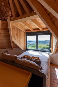 um quarto no sótão com uma cama e uma grande janela em O Moinho 98 - A cozy getaway by the coast na Lourinhã
