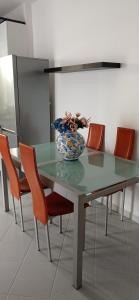 a table with orange chairs and a vase of flowers on it at Casa Mandarino in Ischia