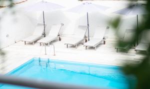una piscina con sillas y sombrillas y una piscina en Apartments by Evita's Resort, en Poros