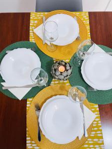 una mesa con platos blancos y vasos en una mesa en Cozy 2-Bedroom Serviced Apartment with Netflix en Puerto de Sagunto