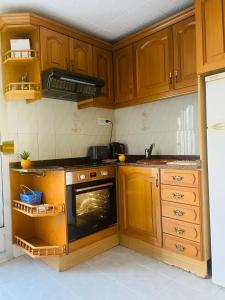 a kitchen with wooden cabinets and an oven at Cozy 2-Bedroom Serviced Apartment with Netflix in Puerto de Sagunto