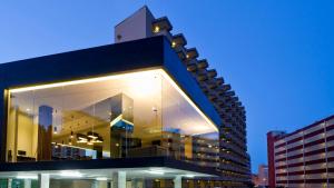 un bâtiment avec une façade en verre la nuit dans l'établissement Hotel Acapulco Benidorm, à Benidorm