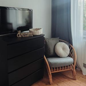 einen Stuhl neben einer Kommode mit einem TV in der Unterkunft Mathilde Zimmervermietung in Lengede